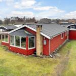 Rotes Holzhaus mit großem Fensterbereich und Garten.