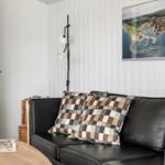 Schwarzes Sofa mit karierten Kissen, Wandbild und Stehlampe im Wohnzimmer.