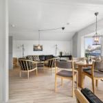 Wohn- und Essbereich mit Holzboden, Sofa, Stühlen und großen Fenstern.