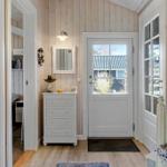 Entryway with white doors, wood-paneled walls, and a vanity. Access to bedroom.