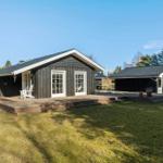 Wooden house with terrace and garden. White windows and door. Background with trees.