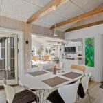 Dining room with round table, white chairs, and wooden beams on ceiling.