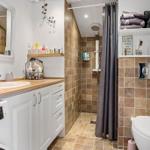Bathroom with shower, sink, and toilet. Wooden countertop and tiles.