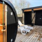 Outdoor area with sauna, lounge chairs, and shower on wooden deck.