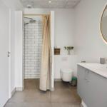 Bathroom with shower, toilet, and sink with gold faucet.