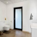 Bathroom with washing machine, toilet, and sink with gold faucet.