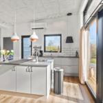 Modern kitchen with island, large window, and view of terrace.