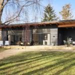 Modern villa with terrace, seating, and surrounding trees.