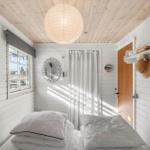 Bedroom with white bed, wooden ceiling, and window. A picture and mirror hang on the wall.