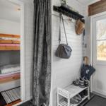 Entrance with coat rack, shoe rack, and view into bedroom with bunk bed.