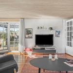 Living area with TV, sofa, and terrace door. Wooden floor and white walls.
