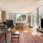Living and dining area with wooden floor, sofa, TV, and table with chairs.