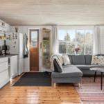 Living kitchen with gray sofa, wooden floor, and large windows.