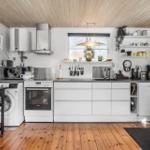 Kitchen with white built-in cabinets, wooden floor, and window. Appliances like dishwasher and refrigerator are present.