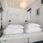 Bedroom with white bed, wooden ceiling, and window.