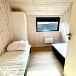 Room with two beds, wooden walls, and a window.