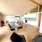 Large open space with dining area, kitchen, and wooden ceiling. Loft bed in the background.