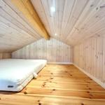 Bedroom with wooden ceiling, walls, floor, and mattress.