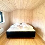 Bedroom with wooden walls and bed with white blankets.