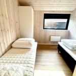 Room with two mattresses, wooden walls, and window