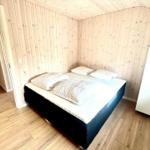 Bedroom with wooden walls and bed with white pillows.