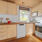 Küche mit Holzschrank, Spüle, Herd und Fenster.