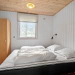 Schlafzimmer mit Bett, Kleiderschrank und Fenster. Holzdecke und weiße Wände.