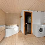 Badezimmer mit Whirlpool, Waschmaschine und Trockner. Holzdecke und Fliesenboden.