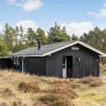 Schwarze Holzhütte mit Schornstein und Schild im Wald
