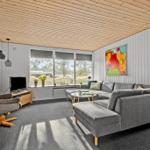 Wohnzimmer mit grauem Sofa, Fernseher und großem Fenster.