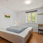 Schlafzimmer mit Bett, Fenster und Stuhl. Holzboden und Wanddekoration.