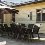 Terrasse mit Tisch, Stühlen und Sonnenschirm vor gelbem Haus