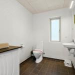 Badezimmer mit Toilette, Waschbecken und Fenster.