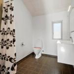 Badezimmer mit Toilette, Waschbecken und Dusche mit floraler Plane.
