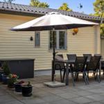 Terrasse mit Tisch, Stühlen und Sonnenschirm vor einem Haus