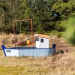 Ein Spielboot mit Schaukel und orangefarbenem Schwimmer im Freien.