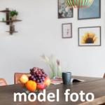 Esstisch mit Obstschale, Bechern und Bildern an der Wand.