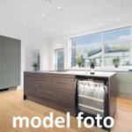 Moderne Küche mit Kücheninsel, integriertem Kühlschrank und großen Fenstern.