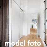 Flur mit Holzboden, Schiebetüren und Spiegeltür. Zimmer im Hintergrund.
