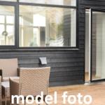 Terrasse mit Rattanmöbeln und Glas-Tür zu Wohnraum
