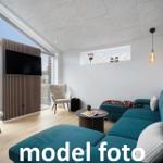 Ein Wohnzimmer mit blauem Sofa, Fernseher und großem Fenster.