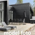 Terrasse mit Liegen, Tisch, Stühlen und Whirlpool neben modernem Holzhaus.