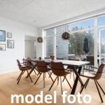 Esszimmer mit Tisch, Stühlen und großem Fensterblick auf die Terrasse.