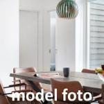 Esstisch mit braunen Stühlen und Obstschale unter einer Lampe.