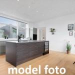 Moderne Küche mit Kücheninsel und Essbereich. Große Fenster und Holzboden.