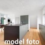 Moderne Küche mit Kücheninsel und Essbereich. Holzboden und große Fenster.