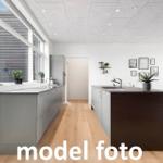 Moderne Küche mit Kücheninsel und Holzboden. Große Fenster und Wanddekoration.