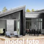 Moderne Holzhütte mit Terrasse, Liegen und Esstisch. Blick in Wohn- und Essbereich.