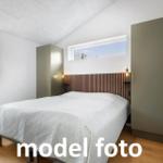 Schlafzimmer mit Bett, Holzfußboden und Fenstern.