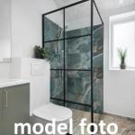 Badezimmer mit Dusche, Waschbecken und Toilette. Fenster mit Pflanze.